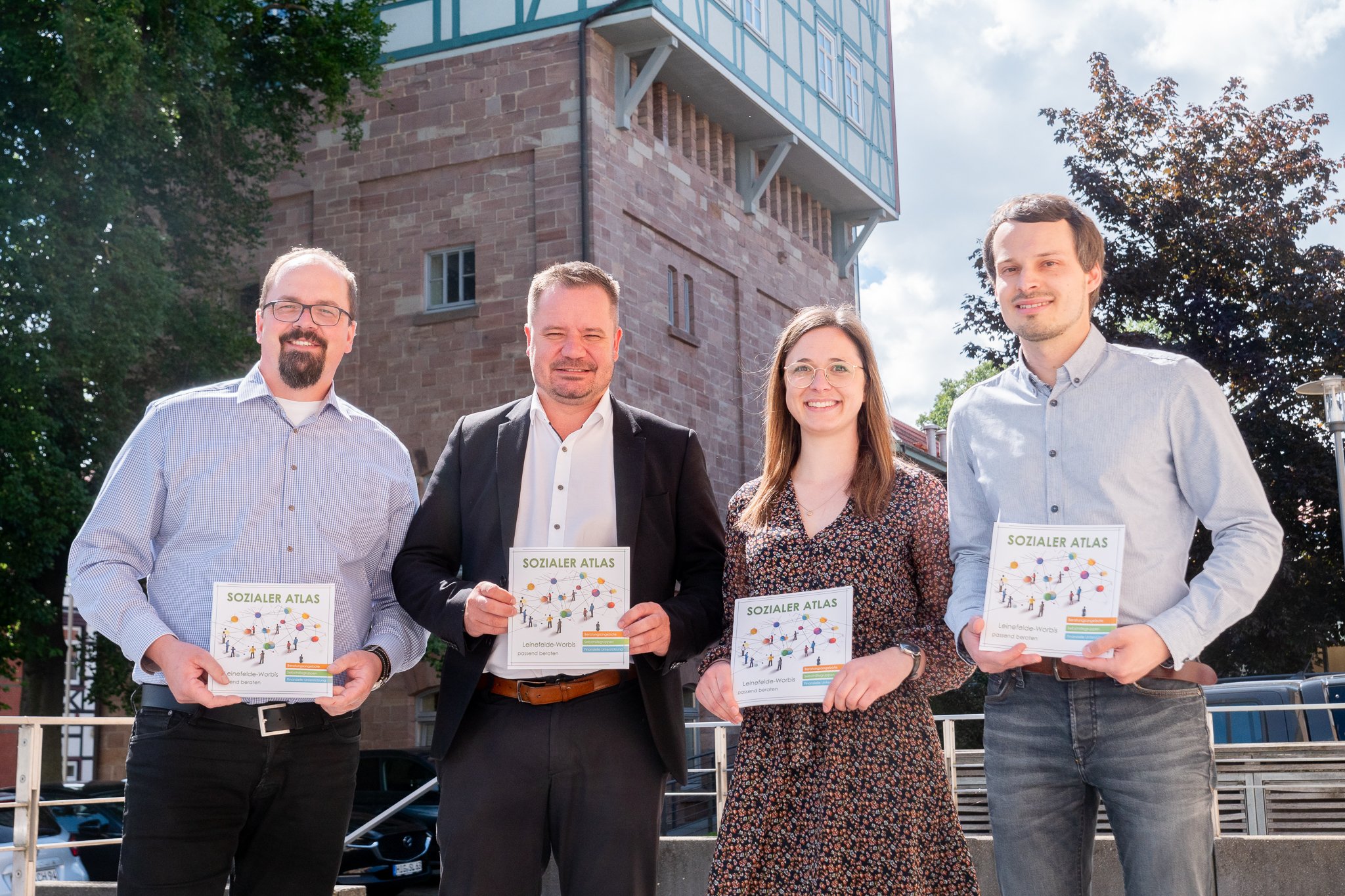 WVL-Geschäftsführer Tino Hartlep, Bürgermeister Christian Zwingmann, Luisa Worell vom Projekt ThINKA und Stadtteilmanager Markus Friedrich bei der offiziellen Übergabe des Sozialen Atlas vor dem Leinefelder Rathaus Wasserturm. 