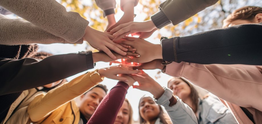A gathering of young adults clasping their hands in unity - Diverse group of university students joining hands in a stack - The notion of human connection, societal bonds, communal Generative AI A gathering of young adults clasping their hands in unity - Diverse group of university students joining hands in a stack - The notion of human connection, societal bonds, communal Generative AI