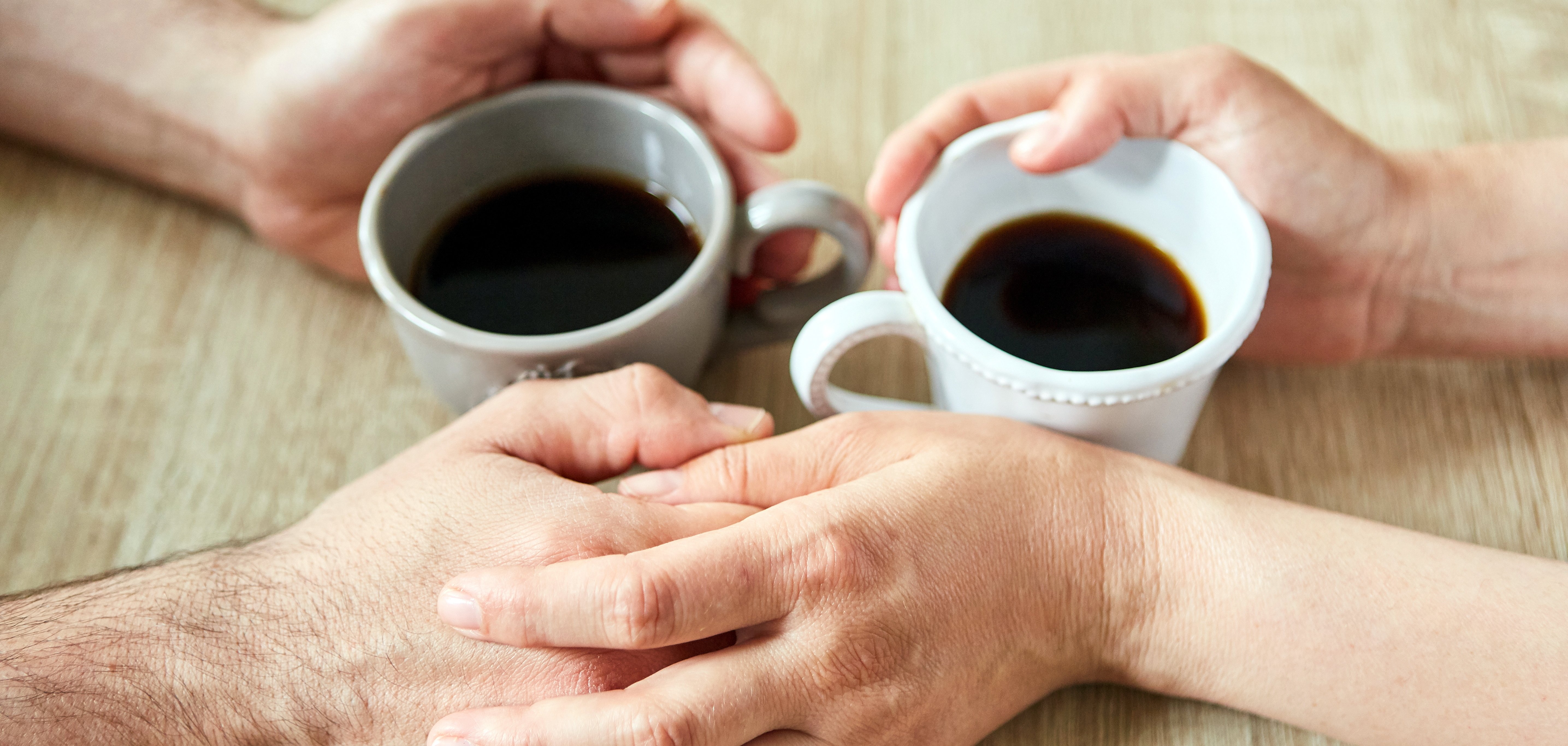 Two hands are touching while drinking coffee