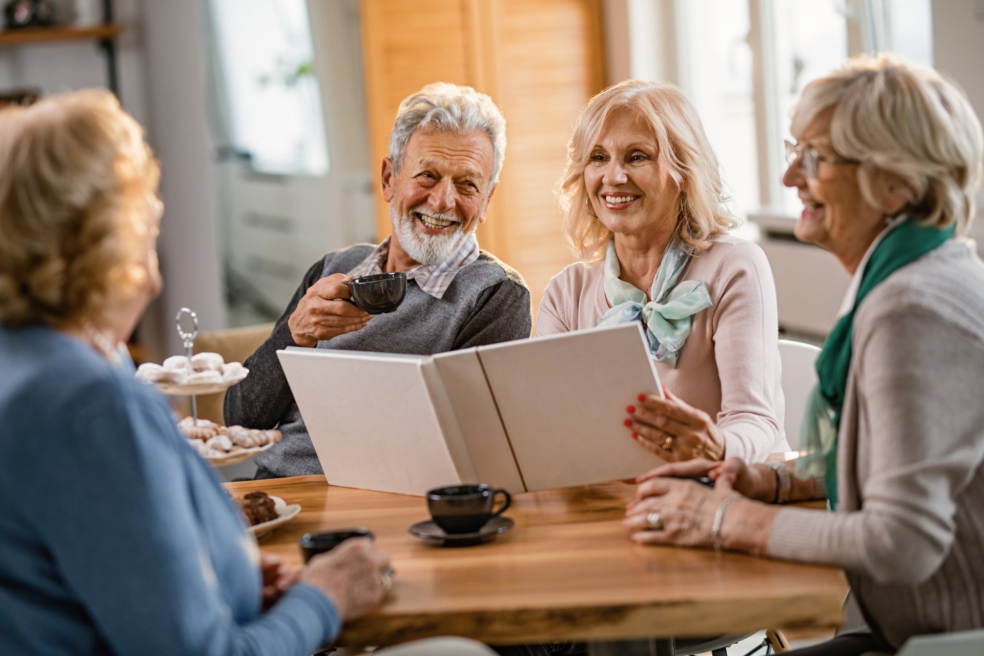 Happy mature friends talking about their memories while looking Happy mature friends talking about their memories while looking