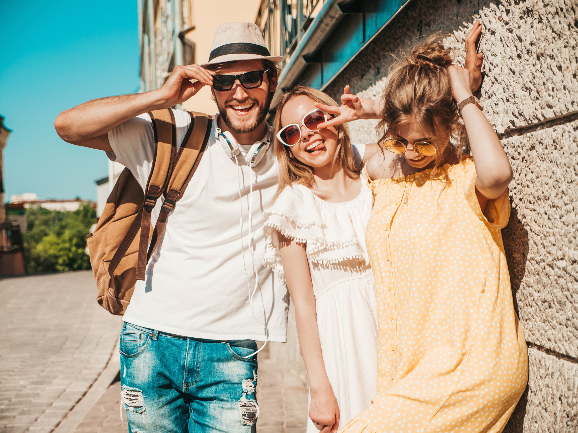 Group of young three stylish friends posing in the street. Fashion man and two cute girls dressed in casual summer clothes. Smiling models having fun in sunglasses.Cheerful women and guy outdoors Group of young three stylish friends posing in the street. Fashion man and two cute girls dressed in casual summer clothes. Smiling models having fun in sunglasses.Cheerful women and guy outdoors