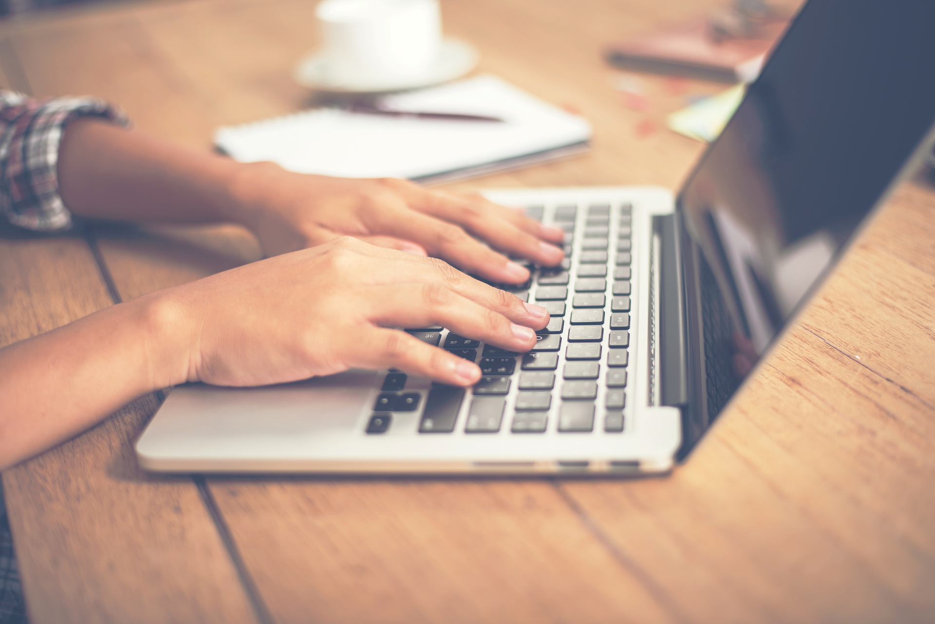 Close-up woman hands typing on laptop in office.
