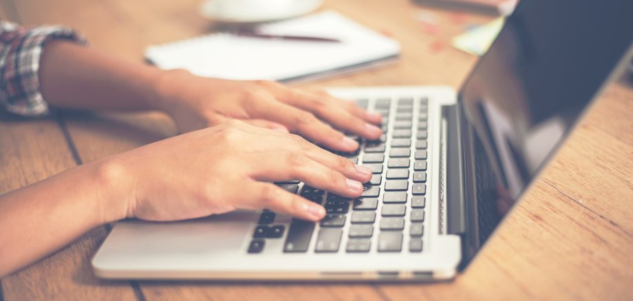 Close-up woman hands typing on laptop in office.