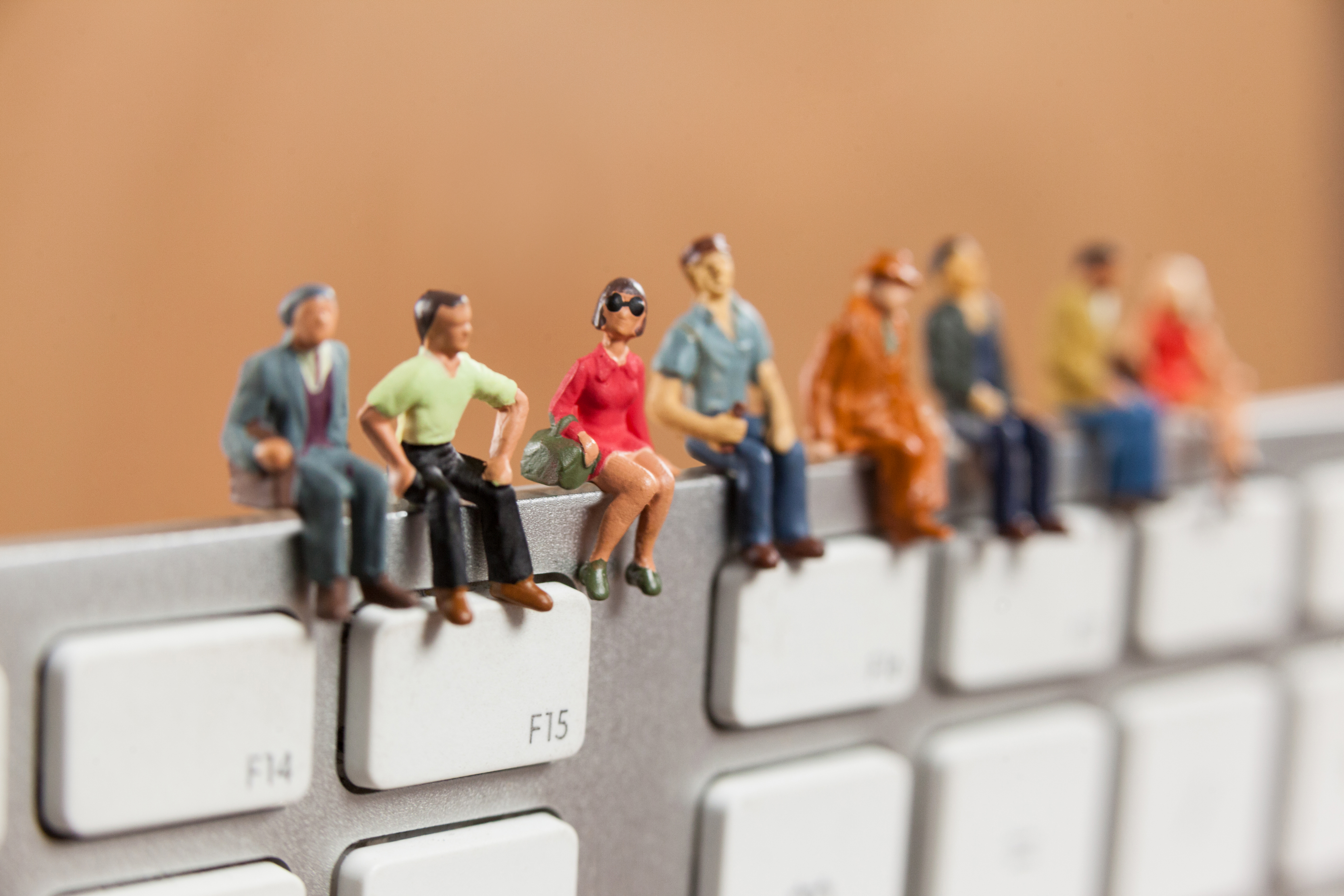 Miniature people sitting on top of keyboard