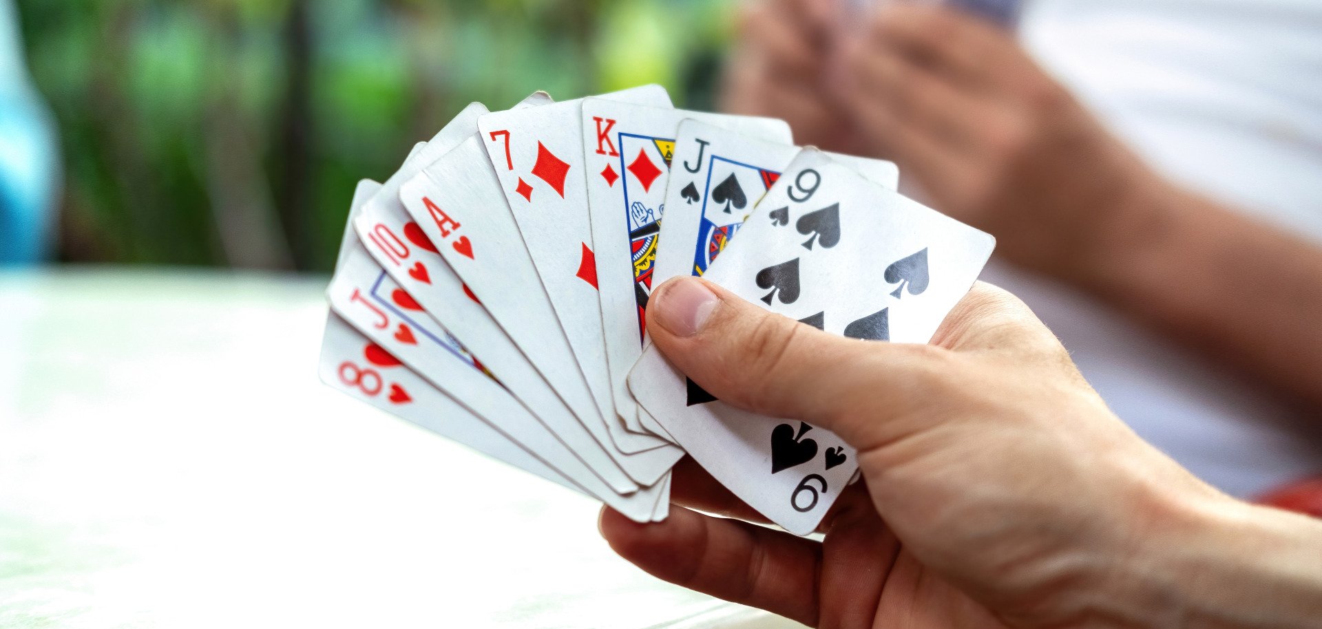 A man playing cards with other people holding a deck