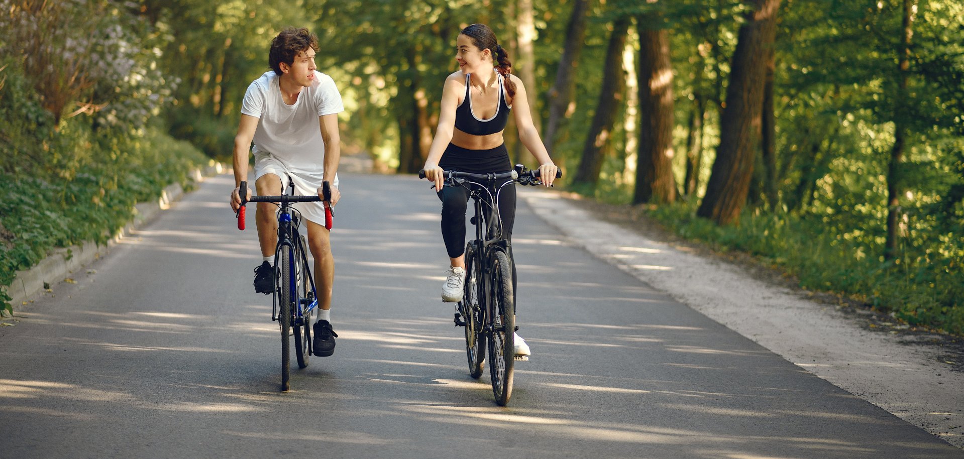 Sports couple riding bikes in summer forest