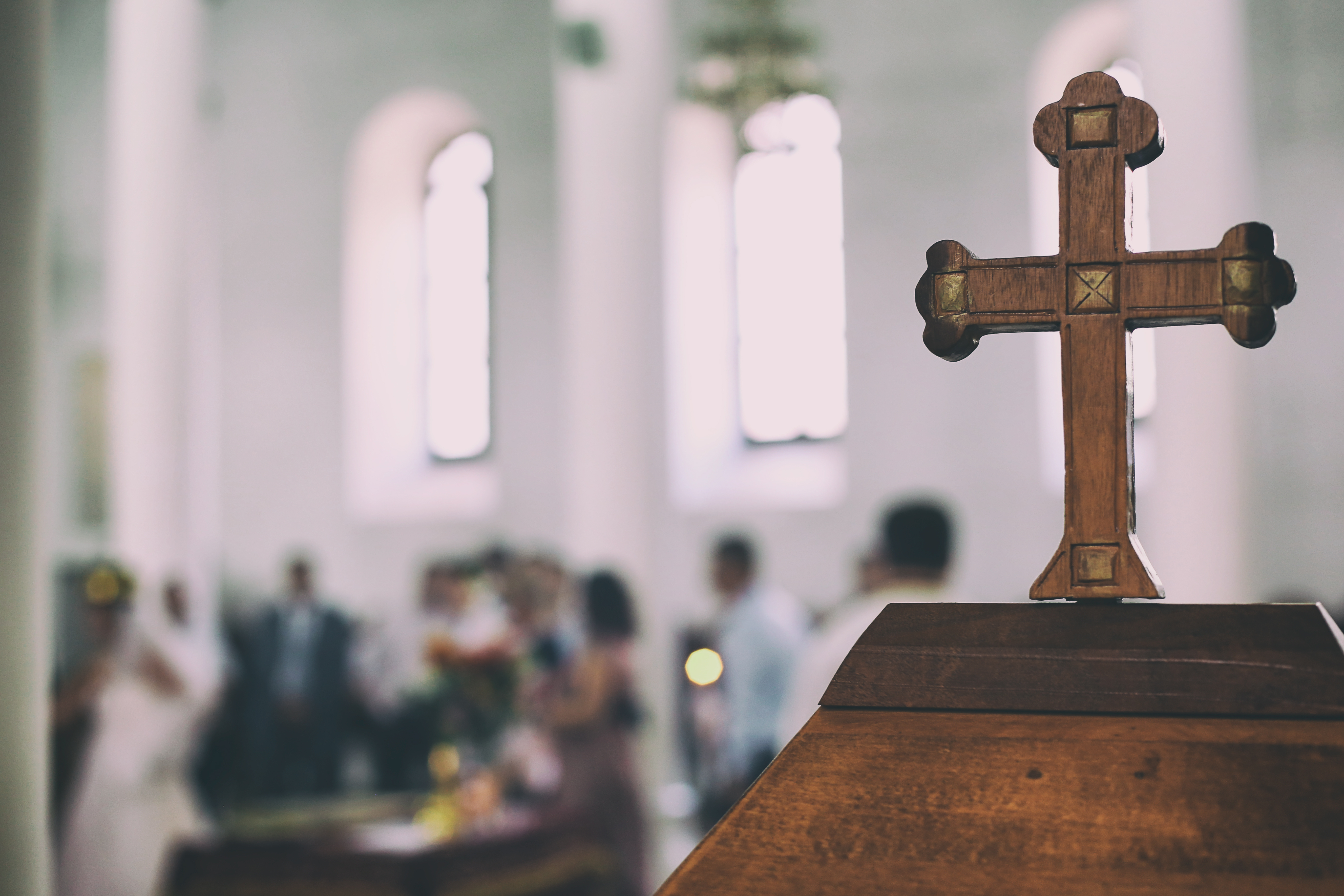 Wedding event in a church the old wooden cross is in a first view and the people are blurred in the background