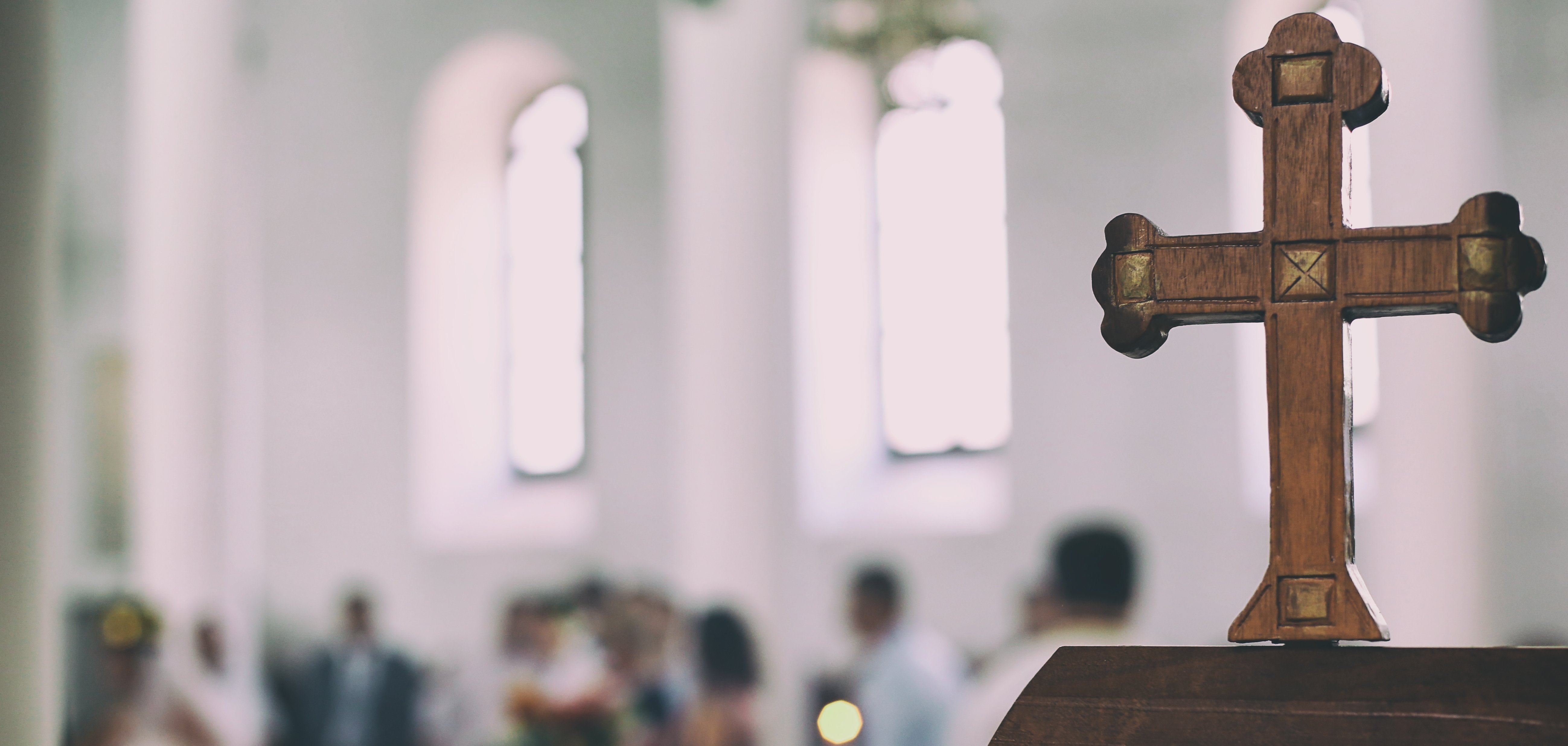 Wedding event in a church the old wooden cross is in a first view and the people are blurred in the background