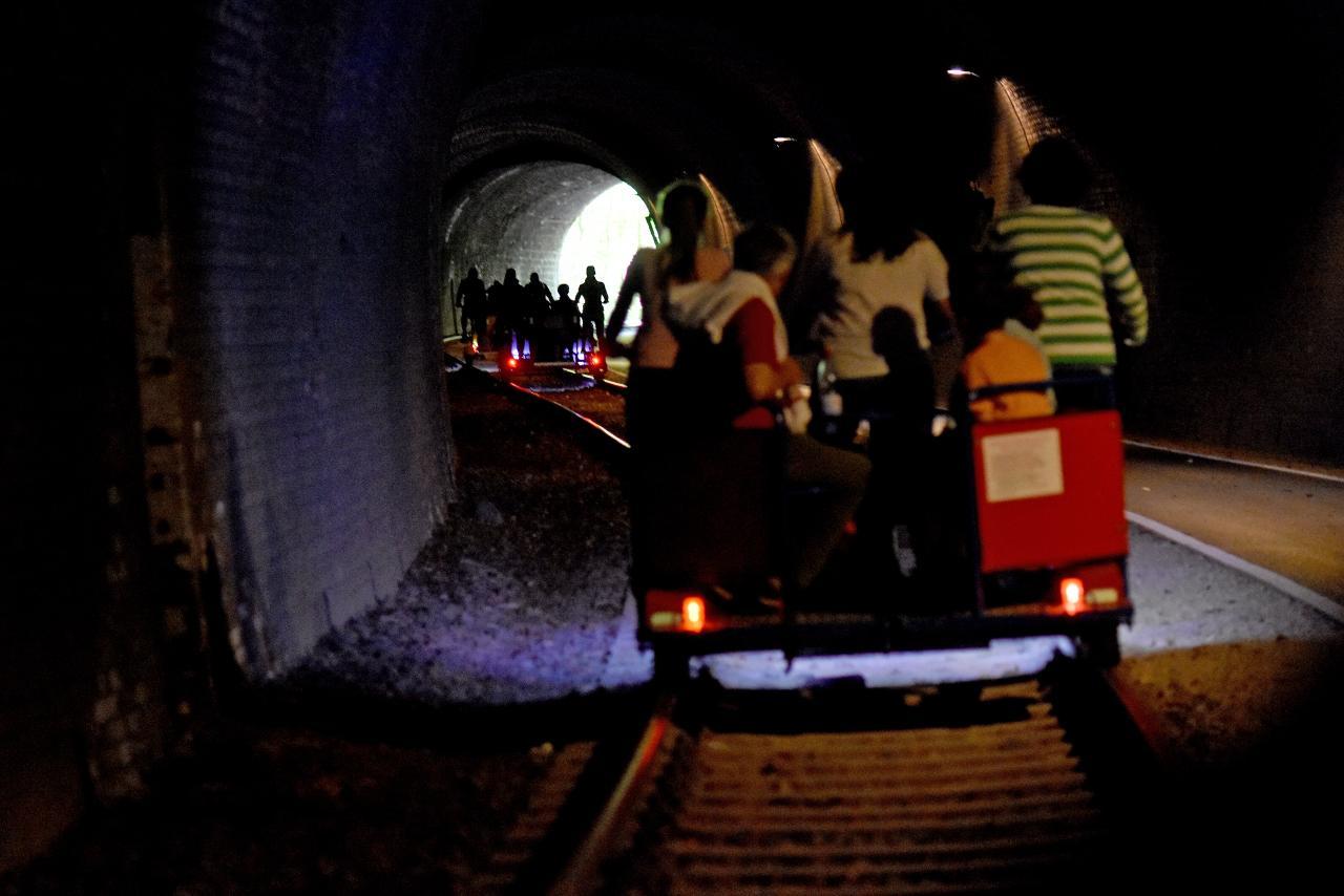 Eine Draisine fährt durch einen Tunnel.